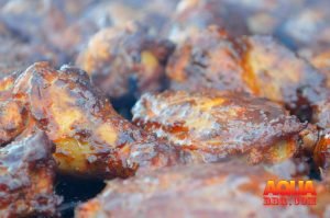 A honey butter glazed lot of chicken wings on a smoker