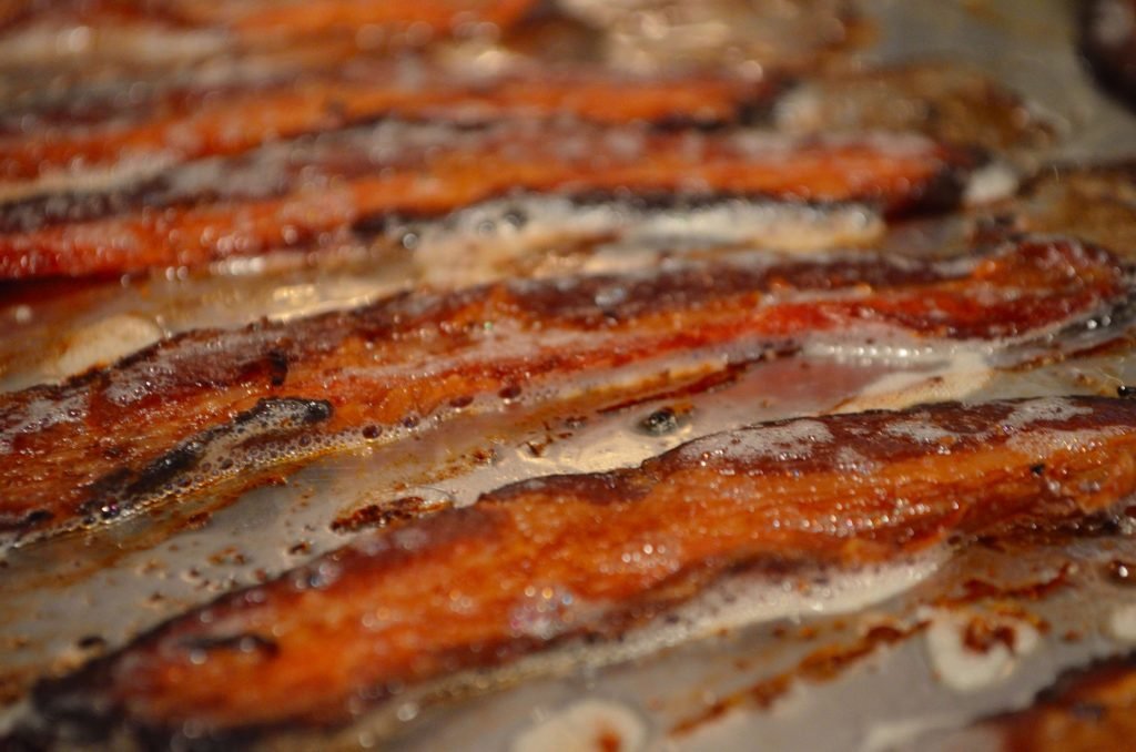Frying the bacon on the Primo always wins- however if you are going to cook it inside try putting it on a sheet pan full in a cold oven and then set it on 400.  Check it in 12-15 minutes, turning it over once.  Let it go for another few minutes.