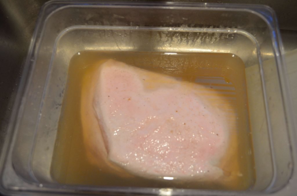 Submerge pork in brine.