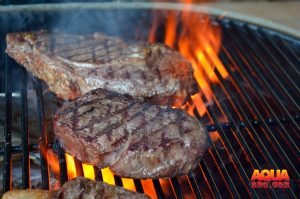 Steaks on a fiery grill being seared