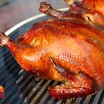 Two chickens being smoked on a grill