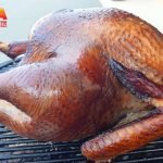 A turkey being smoked on a grill